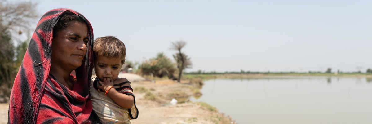 Benazir, 30, stands with her daughter, Oumara, 3, next to stagnant water